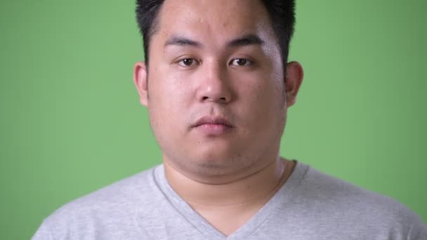 Unga stiliga övervikt asiatisk man mot grön bakgrund — Stockvideo