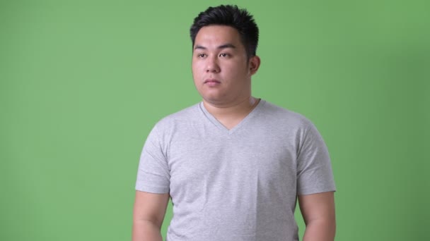 Νεαρό όμορφος υπέρβαρο Ασιατική άνθρωπο ενάντια σε πράσινο φόντο — Αρχείο Βίντεο