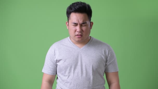 Young handsome overweight Asian man against green background — Stock Video