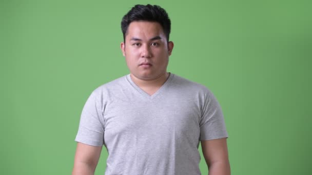 Молодий красивий надмірна вага азіатських людині на зеленому тлі — стокове відео