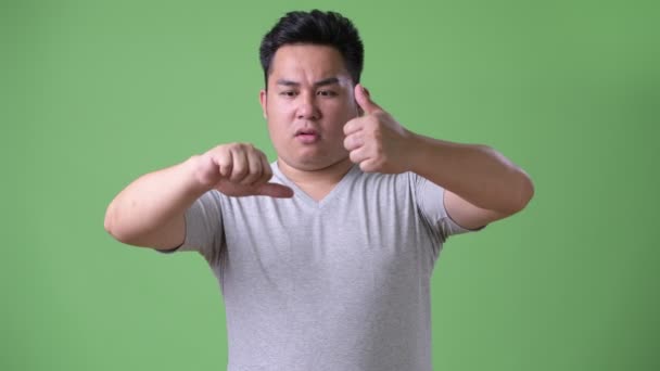 Jonge knappe overgewicht Aziatische man tegen een groene achtergrond — Stockvideo