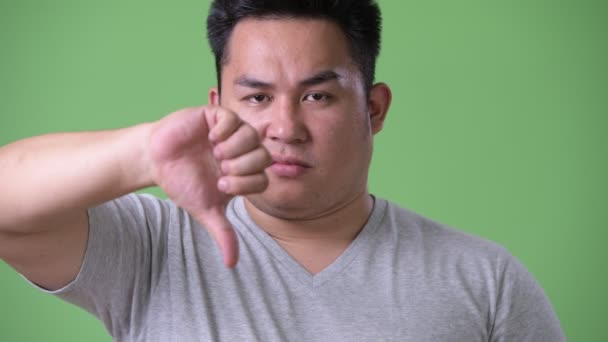 Young handsome overweight Asian man against green background — Stock Video