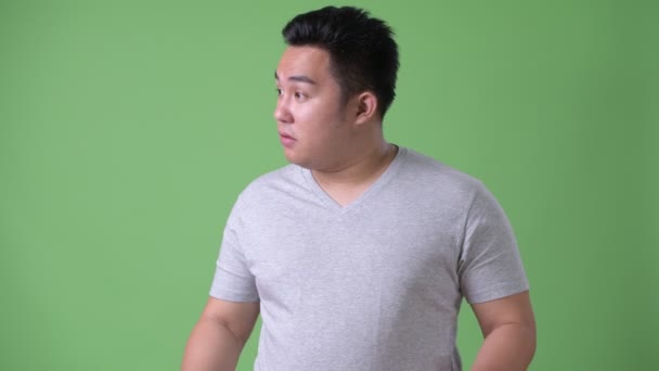 Unga stiliga övervikt asiatisk man mot grön bakgrund — Stockvideo