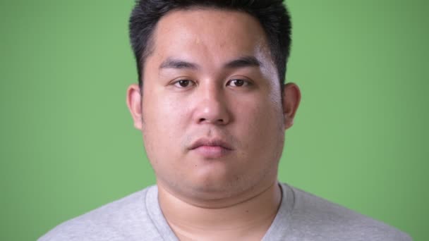 Young handsome overweight Asian man against green background — Stock Video