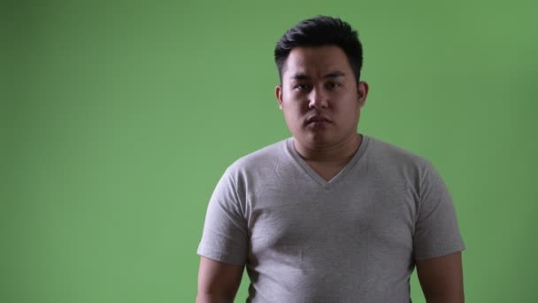 Young handsome overweight Asian man against green background — Stock Video