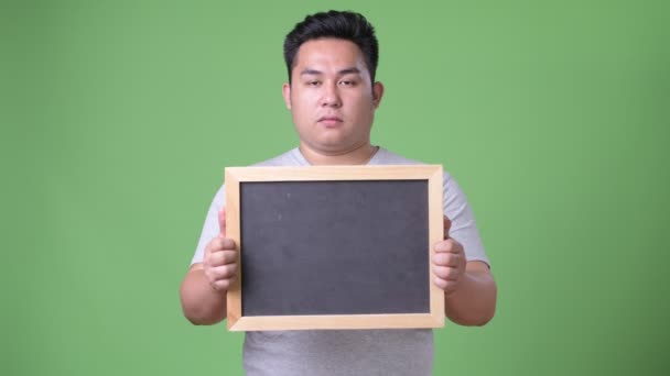 Junge hübsche übergewichtige asiatische Mann vor grünem Hintergrund — Stockvideo