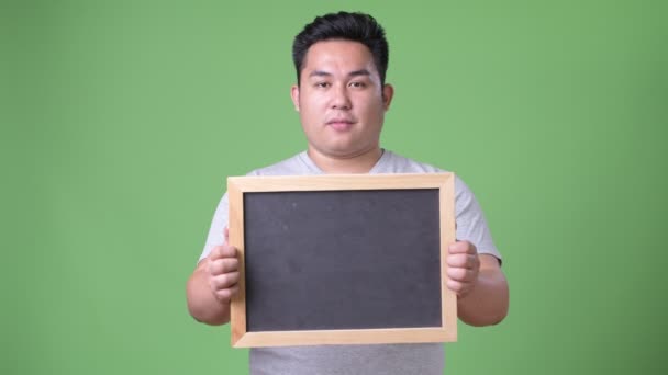 Jonge knappe overgewicht Aziatische man tegen een groene achtergrond — Stockvideo