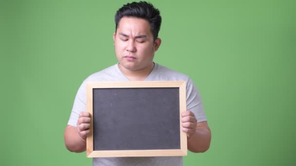 Young handsome overweight Asian man against green background — Stock Video