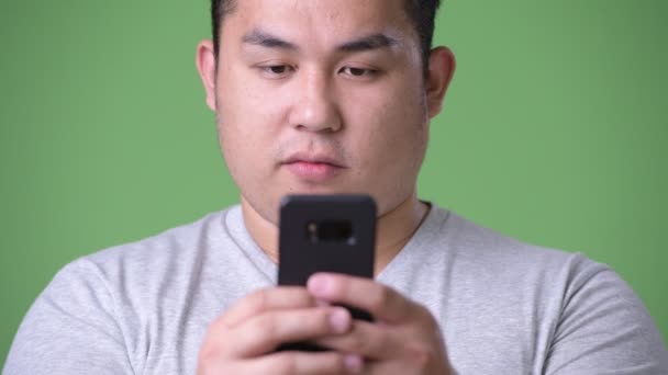 Young handsome overweight Asian man against green background — Stock Video