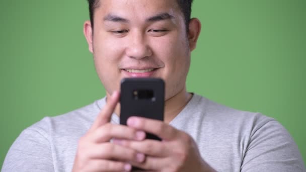 Young handsome overweight Asian man against green background — Stock Video