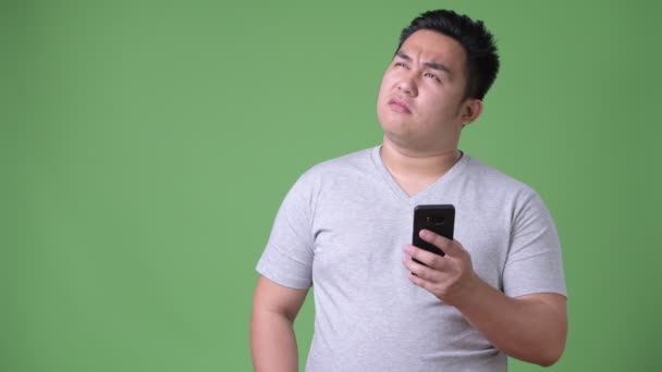 Young handsome overweight Asian man against green background — Stock Video