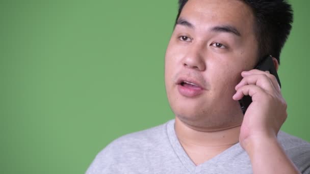 Young handsome overweight Asian man against green background — Stock Video