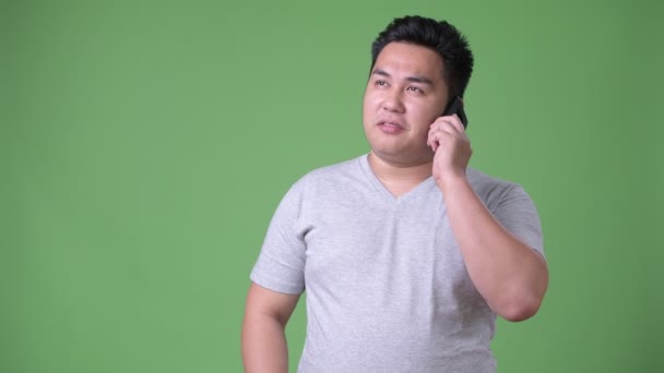 Young handsome overweight Asian man against green background — Stock Video