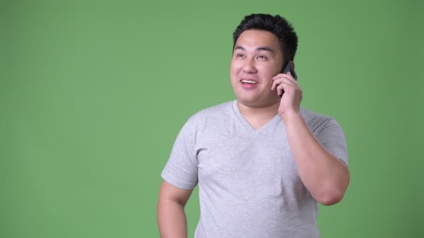 Young handsome overweight Asian man against green background — Stock Video