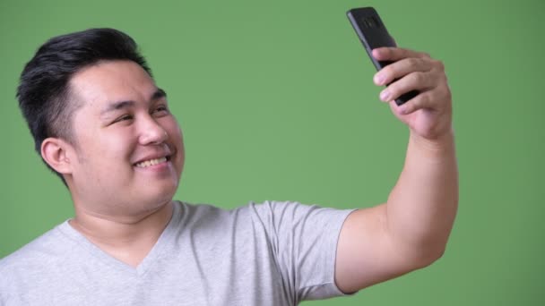 Young handsome overweight Asian man against green background — Stock Video