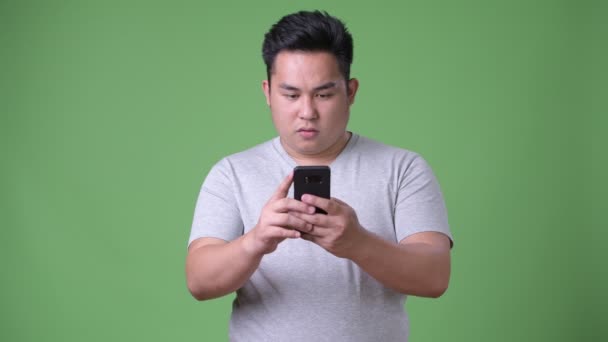 Young handsome overweight Asian man against green background — Stock Video