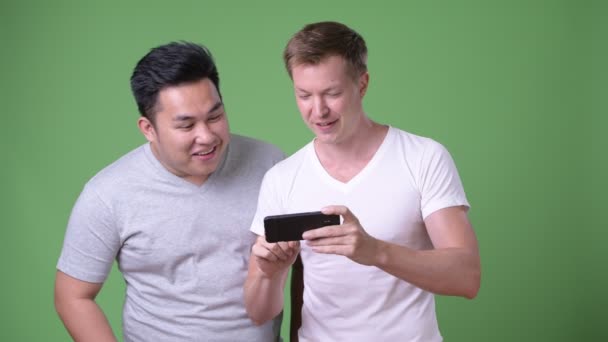 Two young multi-ethnic handsome men together against green background — Stock Video