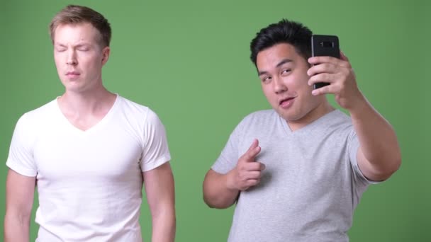 Dva mladí multietnické hezcí muži společně proti zeleným pozadím — Stock video