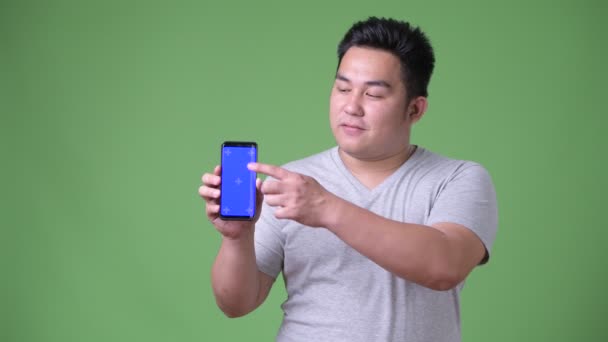 Young handsome overweight Asian man against green background — Stock Video