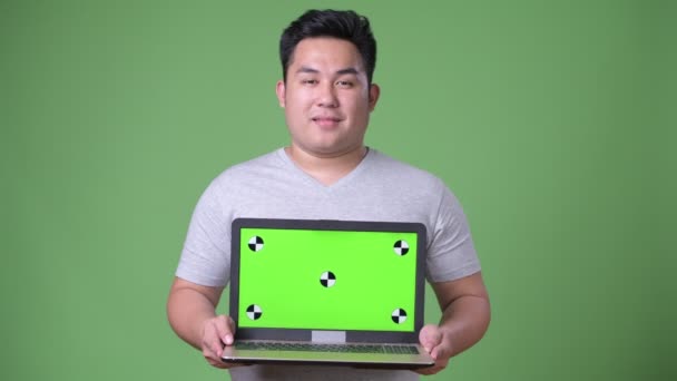 Jonge knappe overgewicht Aziatische man tegen een groene achtergrond — Stockvideo