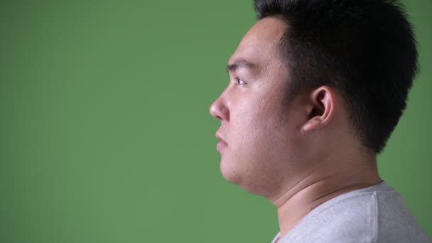 Young handsome overweight Asian man against green background — Stock Video