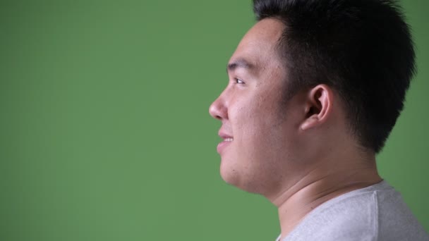 Young handsome overweight Asian man against green background — Stock Video