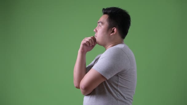 Young handsome overweight Asian man against green background — Stock Video