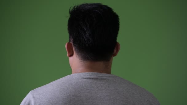 Молодой красивый толстый азиат на зеленом фоне — стоковое видео