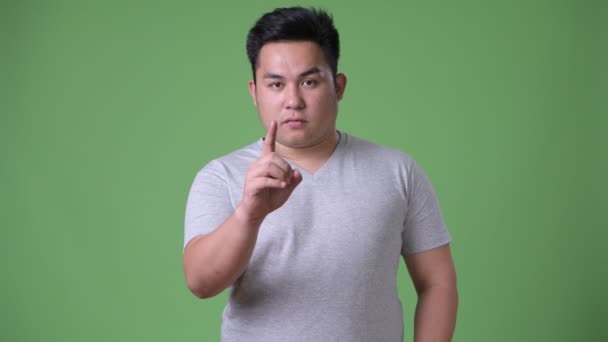 Young handsome overweight Asian man against green background — Stock Video