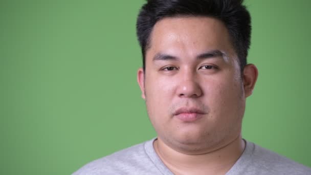 Young handsome overweight Asian man against green background — Stock Video