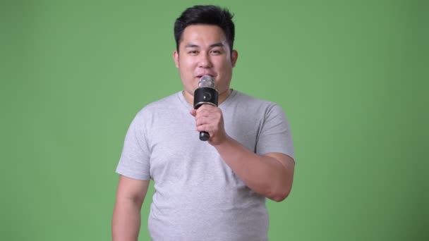 Young handsome overweight Asian man against green background — Stock Video