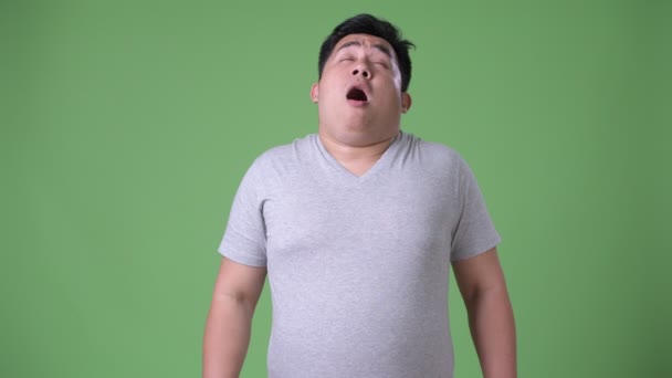 Молодой красивый толстый азиат на зеленом фоне — стоковое видео