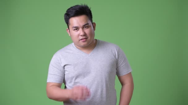 Young handsome overweight Asian man against green background — Stock Video