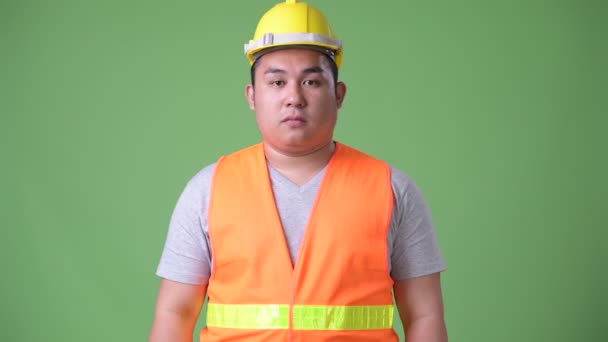 Young handsome overweight Asian man construction worker against green background — Stock Video