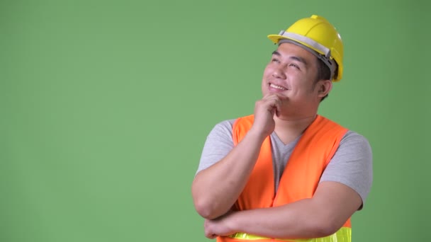 Young handsome overweight Asian man construction worker against green background — Stock Video