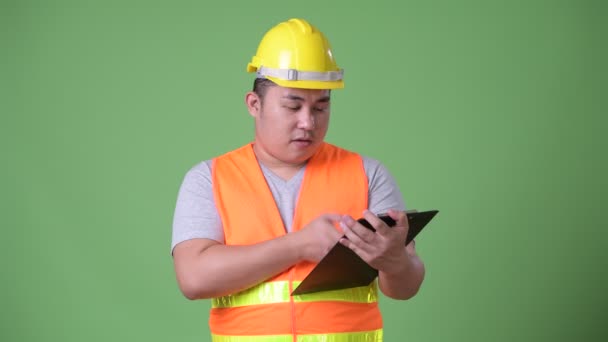 Young handsome overweight Asian man construction worker against green background — Stock Video