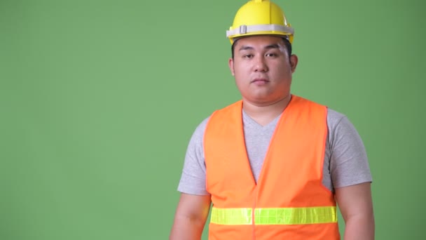 Joven guapo sobrepeso asiático hombre construcción trabajador contra verde fondo — Vídeo de stock