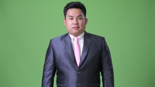 Jeune bel homme d'affaires asiatique en surpoids sur fond vert — Video