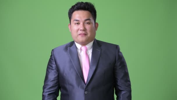 Jeune bel homme d'affaires asiatique en surpoids sur fond vert — Video