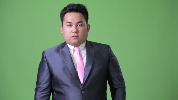 Mladý pohledný nadváhu asijský podnikatel proti zeleným pozadím — Stock video