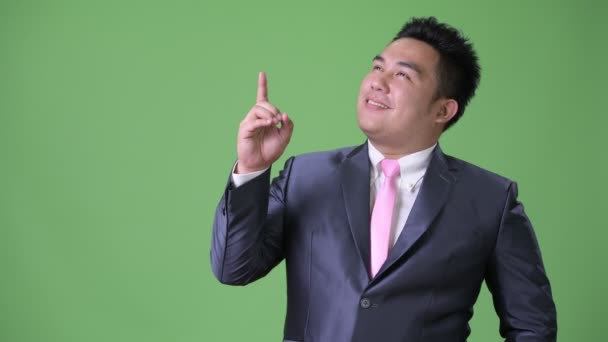 Young handsome overweight Asian businessman against green background — Stock Video