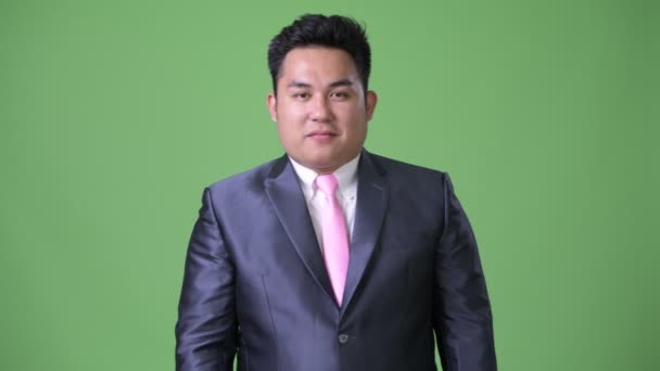 Jeune bel homme d'affaires asiatique en surpoids sur fond vert — Video