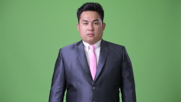 Νέος όμορφος υπέρβαροι Ασίας επιχειρηματίας ενάντια σε πράσινο φόντο — Αρχείο Βίντεο