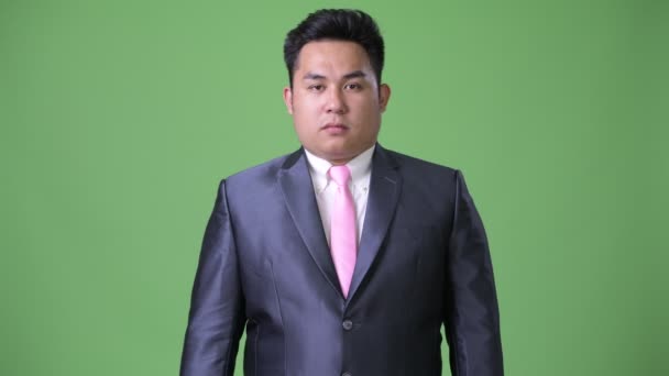 Jeune bel homme d'affaires asiatique en surpoids sur fond vert — Video