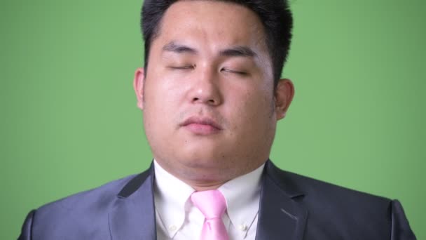 Junge hübsche übergewichtige asiatische Geschäftsmann vor grünem Hintergrund — Stockvideo
