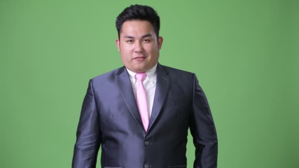 Mladý pohledný nadváhu asijský podnikatel proti zeleným pozadím — Stock video