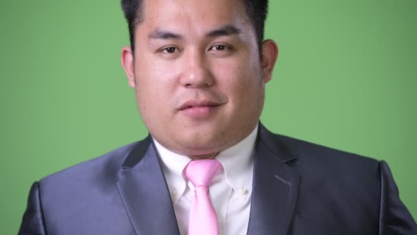 太りすぎの若いハンサムな緑の背景にアジア系のビジネスマン — ストック動画