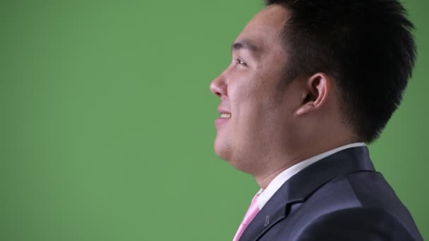 Jonge knappe overgewicht Aziatische zakenman tegen groene achtergrond — Stockvideo
