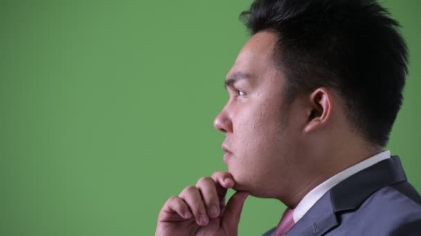 Young handsome overweight Asian businessman against green background — Stock Video