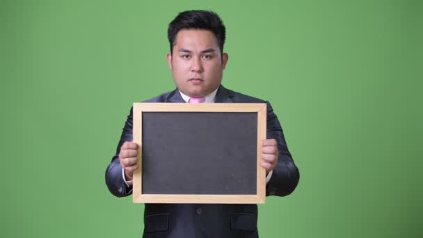 Jeune bel homme d'affaires asiatique en surpoids sur fond vert — Video